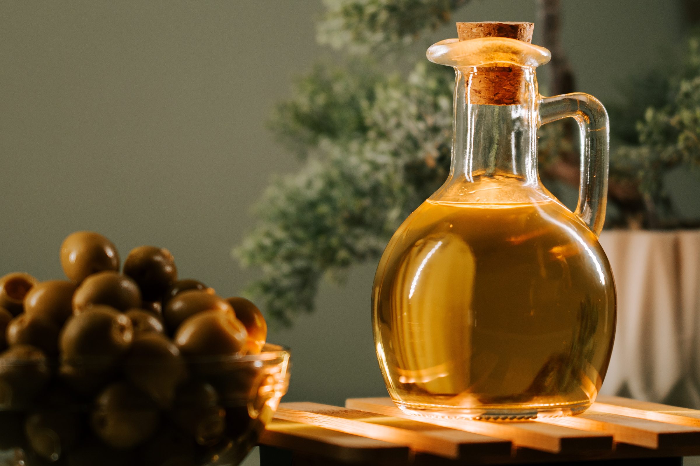 Istrian olive oil in a glass carafe beside a bowl of olives