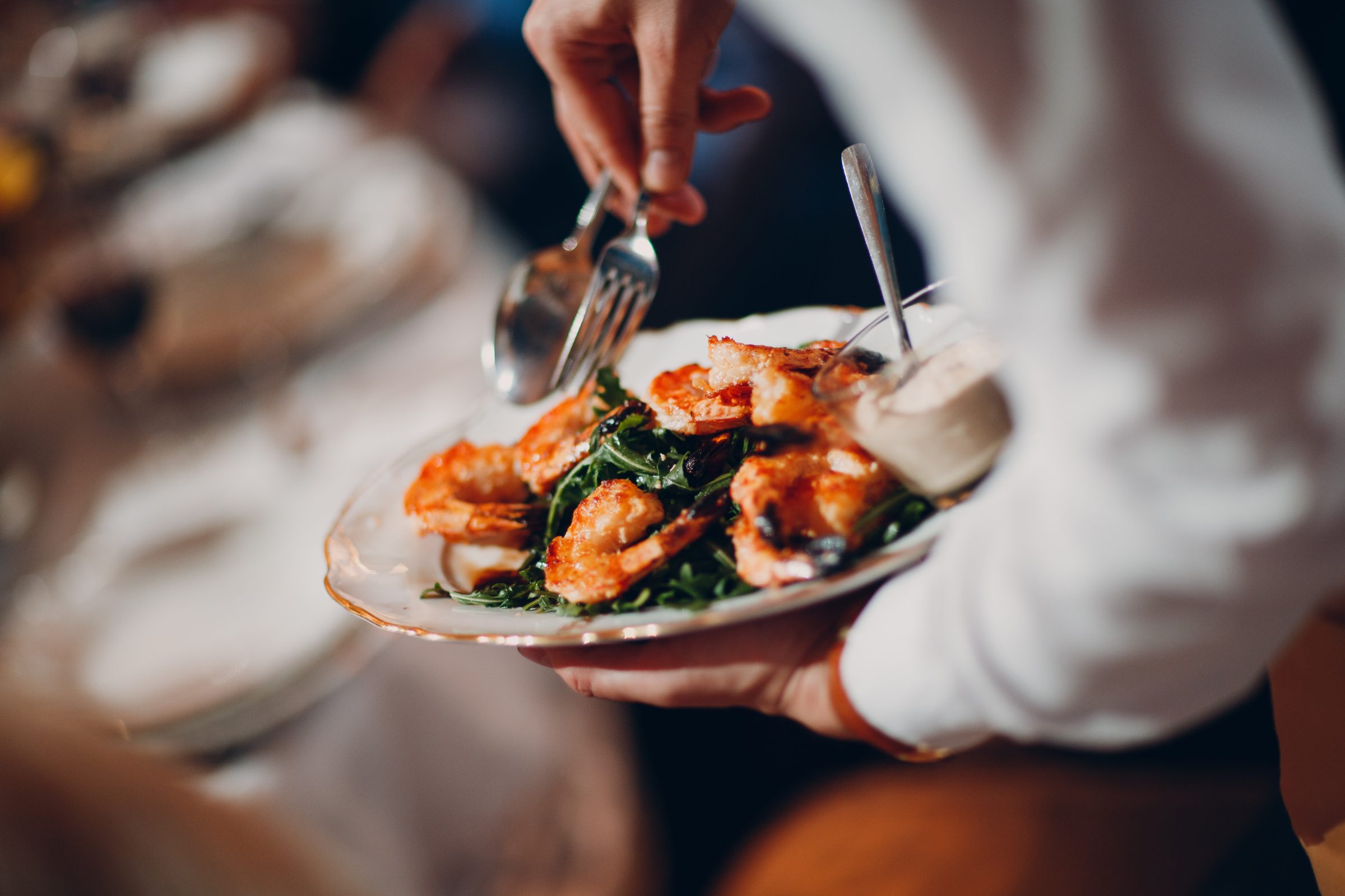 A plate of grilled prawns on rocket being served